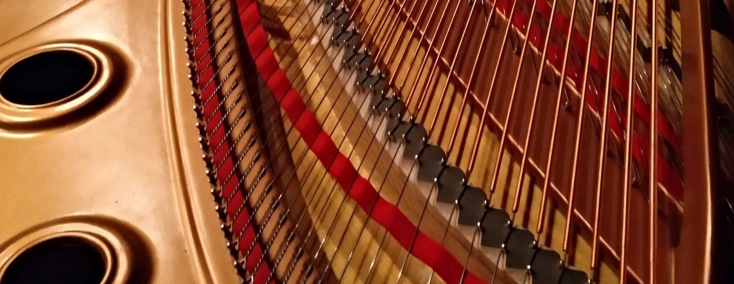 Manos expertas restaurando la maquinaria de un piano antiguo, mostrando el cuidado artesanal